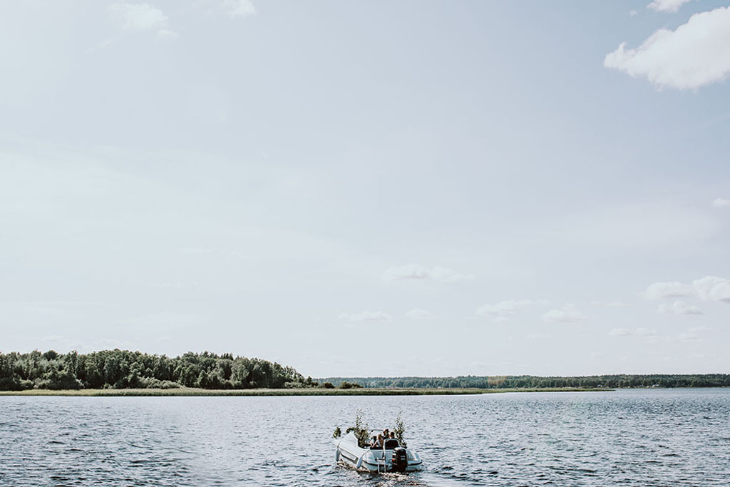 Brudparet åker båt på sjön Vidöstern mot festlokalen i Toftaholm